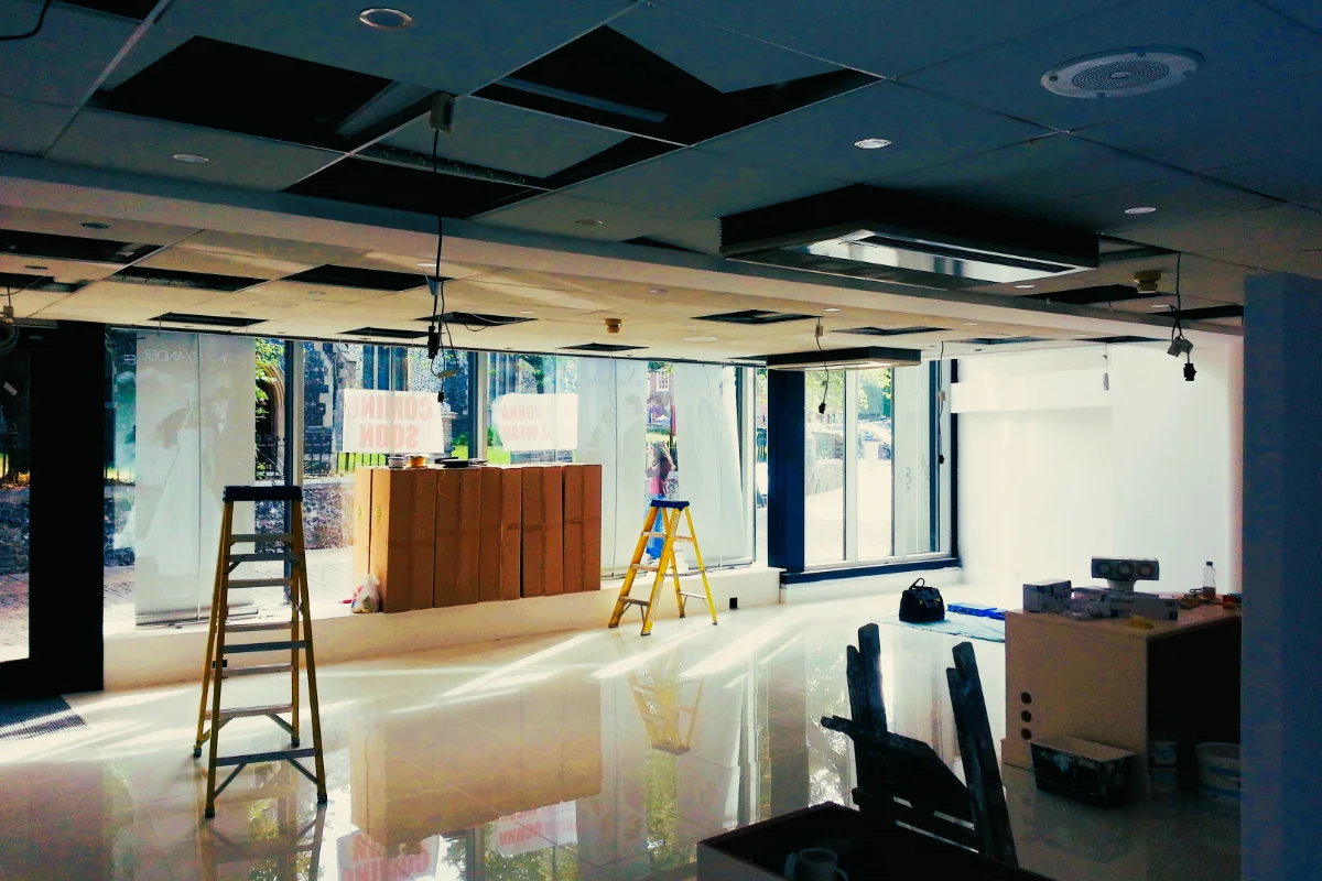 Commercial Electrical Installation in Progress Commercial retail interior undergoing electrical and ceiling installation work with ladders and exposed fittings.